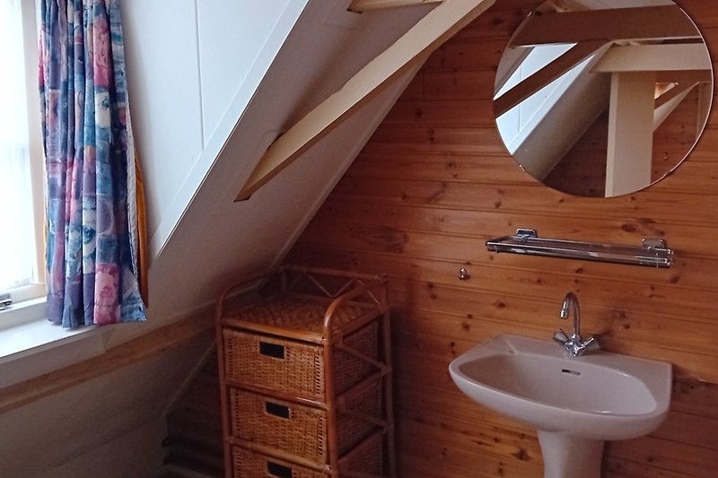 Mooie badkamer met houten kasten, spiegel en verlichting.