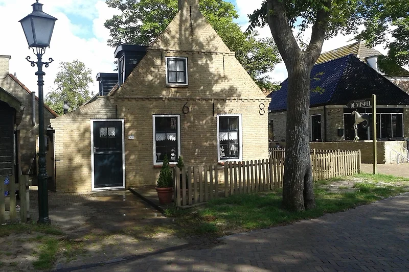 Prachtig huis met houten gevel, sfeervolle ramen en groene planten.