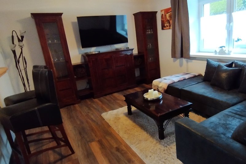 Gemütliches Wohnzimmer mit bequemer Couch, Holzboden und Fernseher