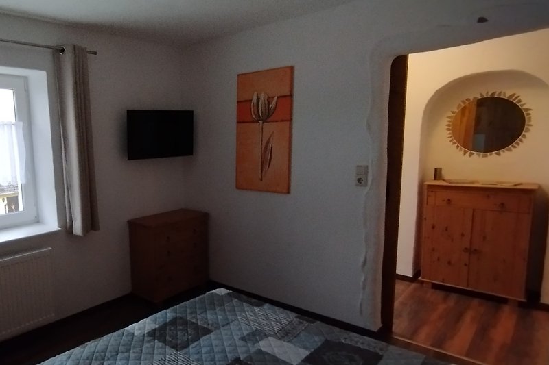 Gemütliches Schlafzimmer mit Holzbett, Fernseher und stilvoller Inneneinrichtung