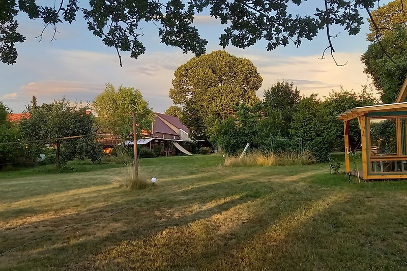 Schönes Cottage mit grünem Garten und malerischem Sonnenuntergang.