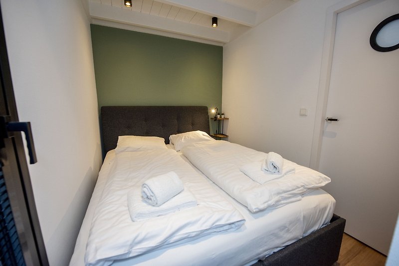Een comfortabele slaapkamer met een groot raam en houten meubels.
