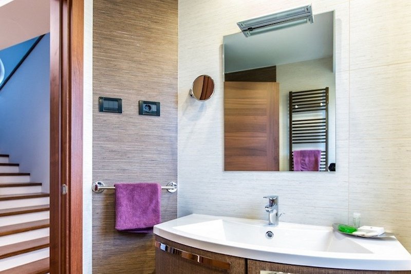 Prekrasna kupaonica s ljubičastim umivaonikom i drvenim podom.