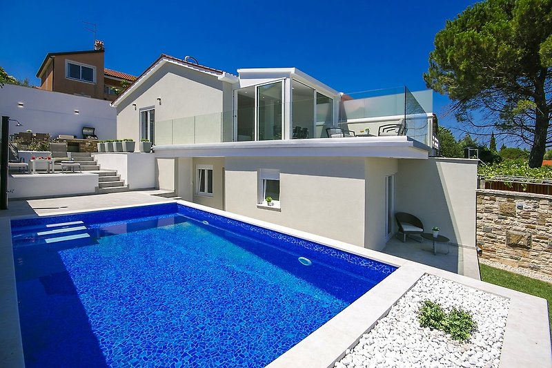 A beautiful property with a swimming pool, blue sky, and water.