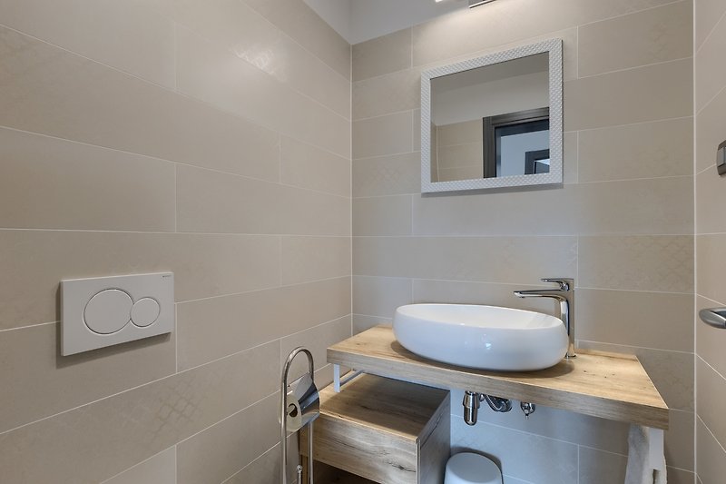 Moderne Badezimmerausstattung mit Holzboden und Keramikwaschbecken.