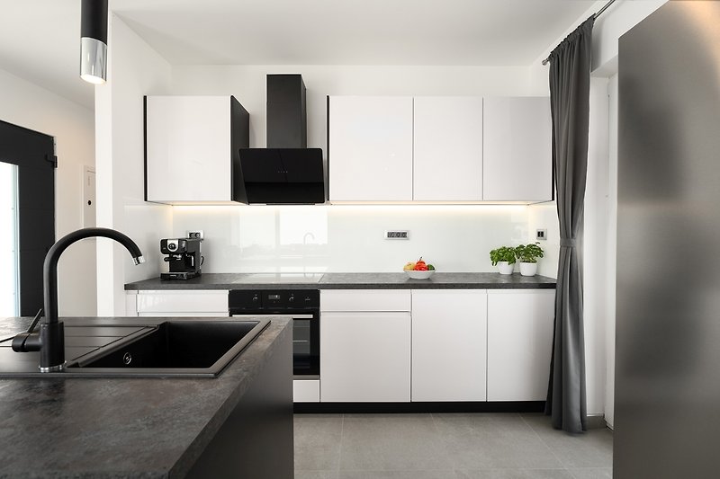Moderne Küche mit grauen Schränken, Arbeitsplatte und Wasserhahn.