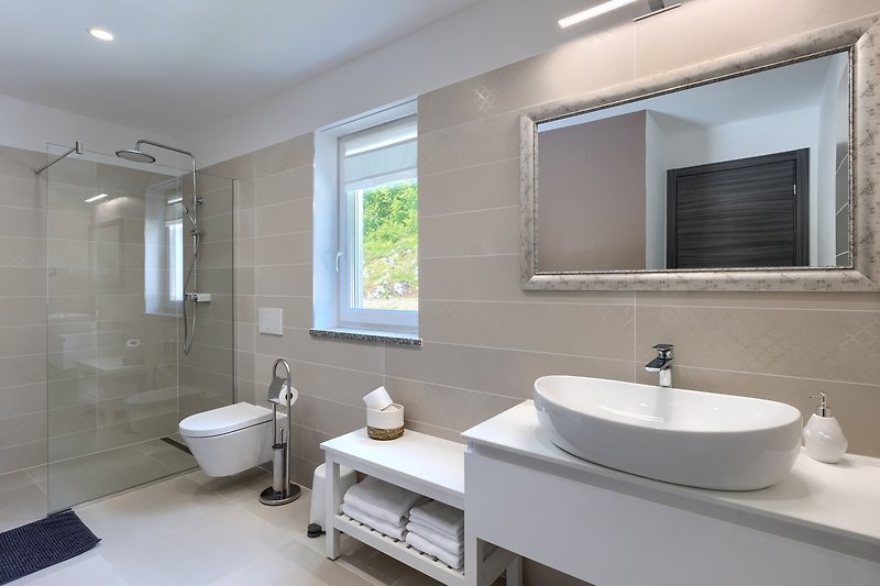 Moderne Badezimmereinrichtung mit Spiegel, Waschbecken und Armatur.