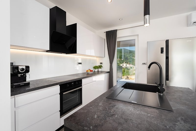 Moderne Küche mit Holzboden, Arbeitsplatte und Fenster - perfekt für einen stilvollen Urlaub.
