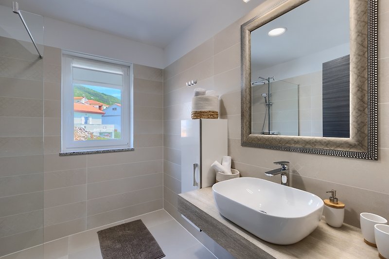 Moderne Badezimmereinrichtung mit Spiegel, Waschbecken und Armatur.