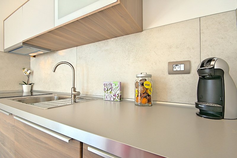 A modern kitchen with a sleek countertop, tap, and cabinetry.