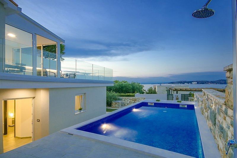 A luxurious poolside retreat with stunning ocean views and modern outdoor furniture.
