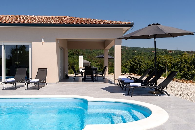 Schwimmbad, Sonnenliegen und moderne Architektur - perfekt für einen entspannten Urlaub.
