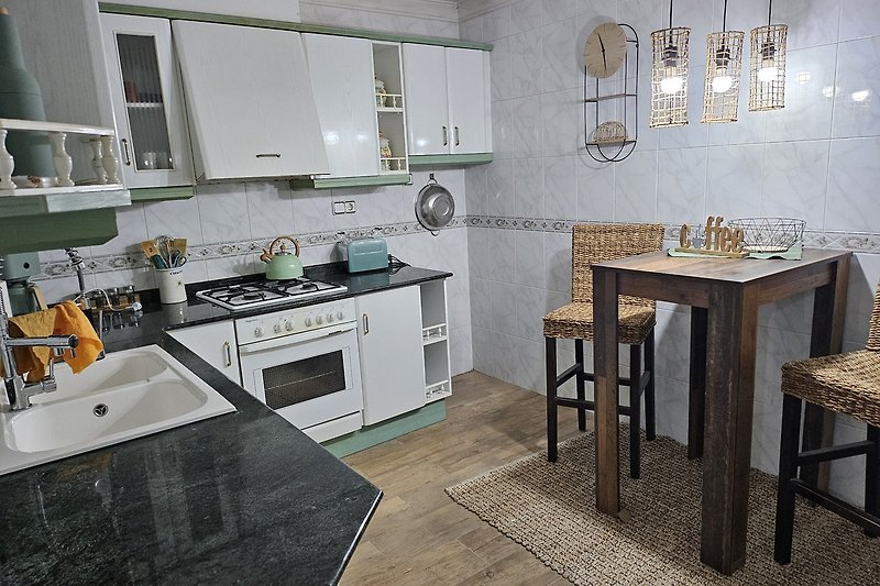 Moderne Küche mit grauen Schränken, Holzfußboden und Edelstahl-Spüle.