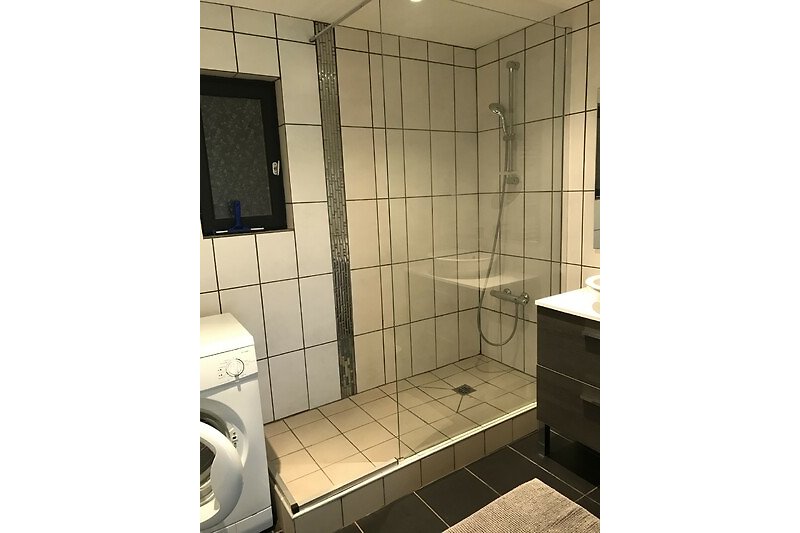 Schwarze Badezimmerausstattung mit Glasdusche und Fliesenboden.