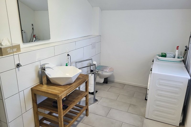 Gemütliches Badezimmer mit Spiegel, Waschbecken und Holzboden.