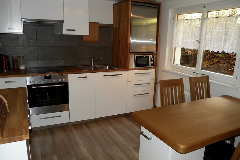 A modern 4-seater, fully equipped kitchen with wooden countertop, dishwasher and TV.