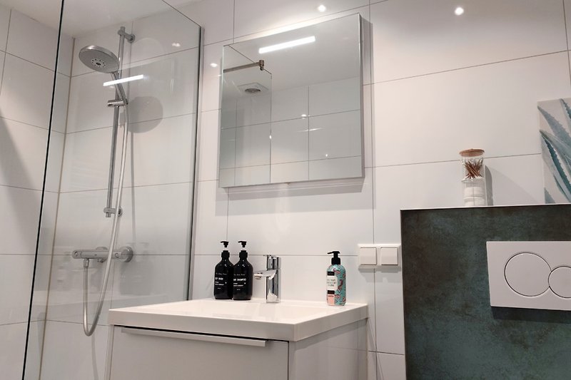 Modernes Badezimmer mit Glasdusche, Aluminiumarmaturen und Fliesen.