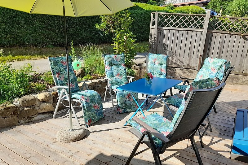 Schöne Terrasse mit blauem Tisch, Stühlen und Sonnenschirm.