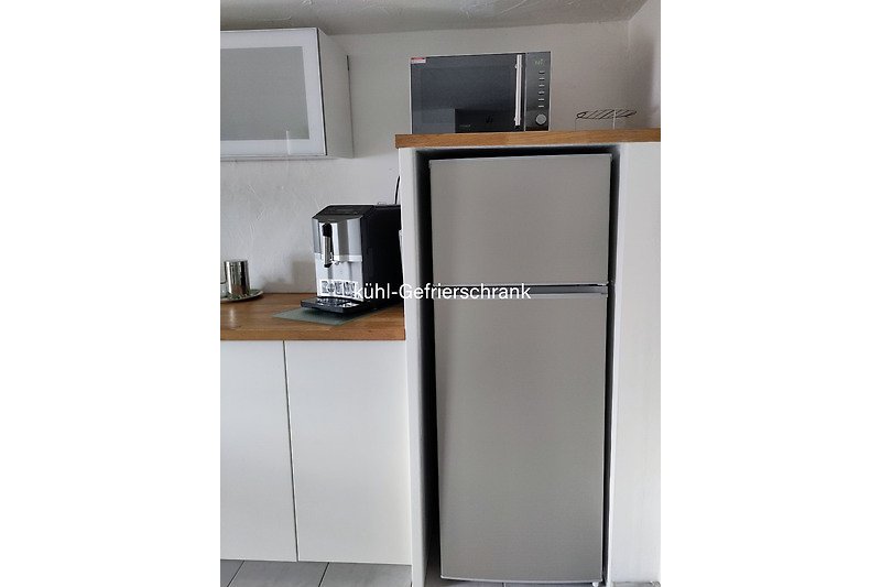 Moderne Küche mit hochwertigen Geräten wie Kaffeevollautomat , Kühl-Gefrierkombination, Mikrowelle u.a.