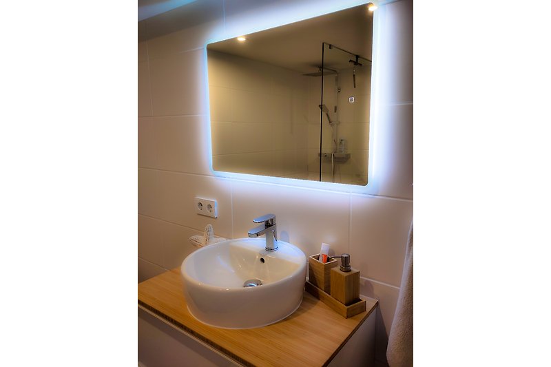 Hochwertiges Badezimmer mit Spiegel, Waschbecken und stilvoller Beleuchtung.