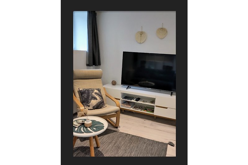 Wohnzimmer mit grossem Smart-TV und bequemem Sessel