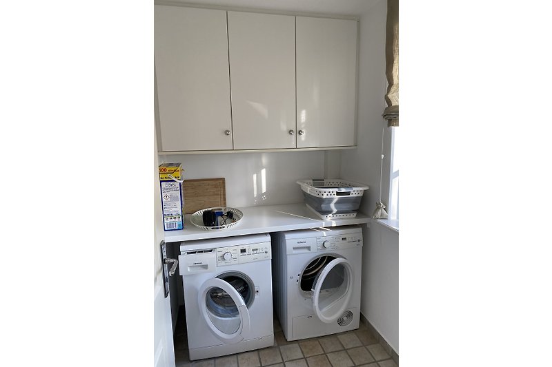 Der Hauswirtschaftsraum  mit Waschmaschine, Trockner und zusätzlichem Stauraum