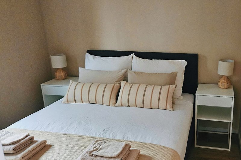 Stijlvol slaapkamer met houten bed, comfortabele kussens en sfeervolle lamp.