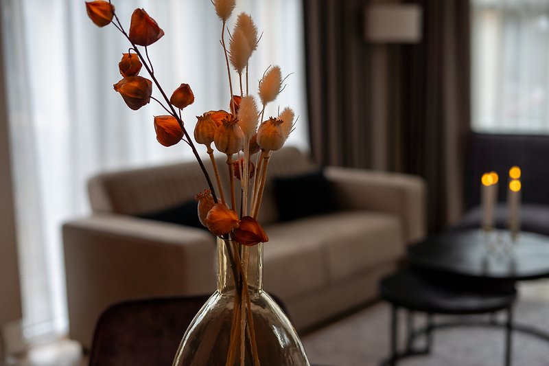 Schöner Tisch mit Blumenarrangement und Glasflasche.