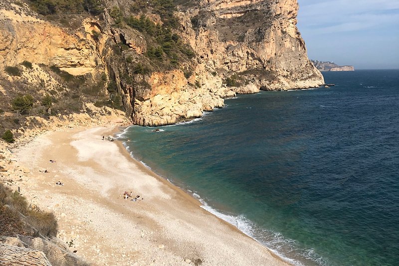 Cala Moruig mit Blick auf azurblaues Meer und felsige Küste.