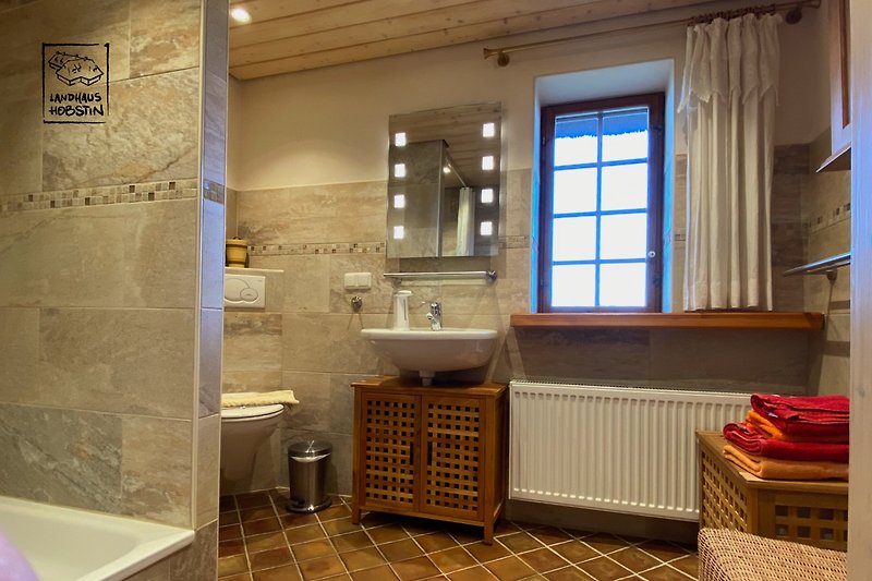 Schönes Duschbad mit Fenster, Spiegel und Waschbecken.