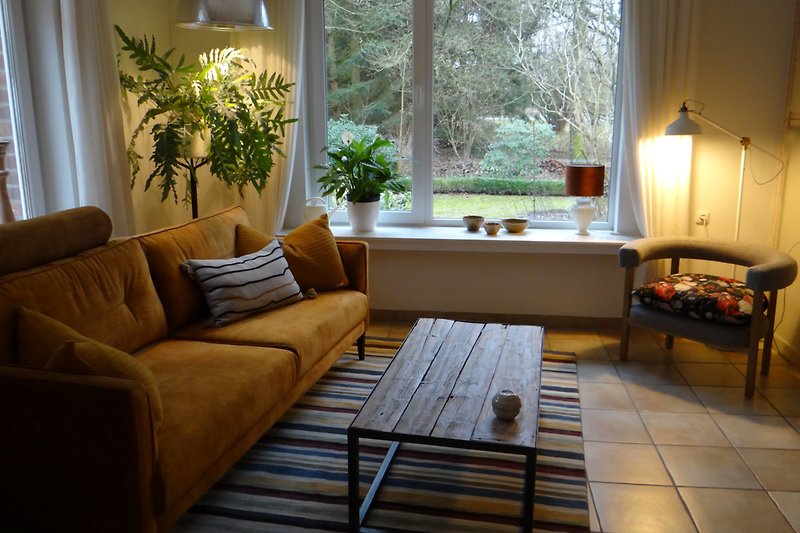Gemütliches Wohnzimmer mit bequemer Couch und großen Fenstern.