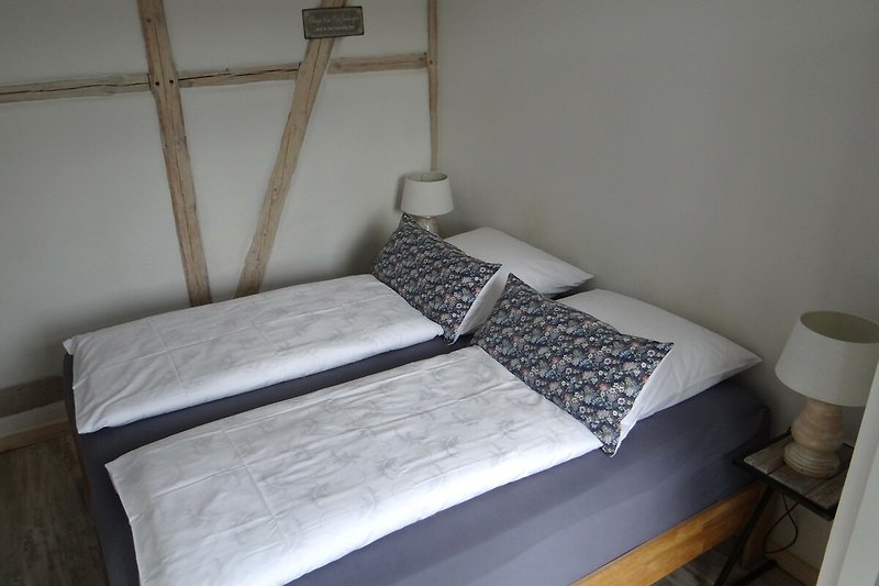 Schlafzimmer mit sichtbarem Fachwerk und Lehmputz für ein gutes Raumklima.