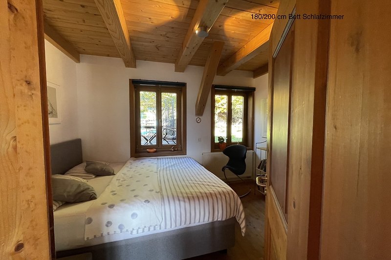 Ein komfortables Schlafzimmer mit Holzmöbeln und großen Fenstern.