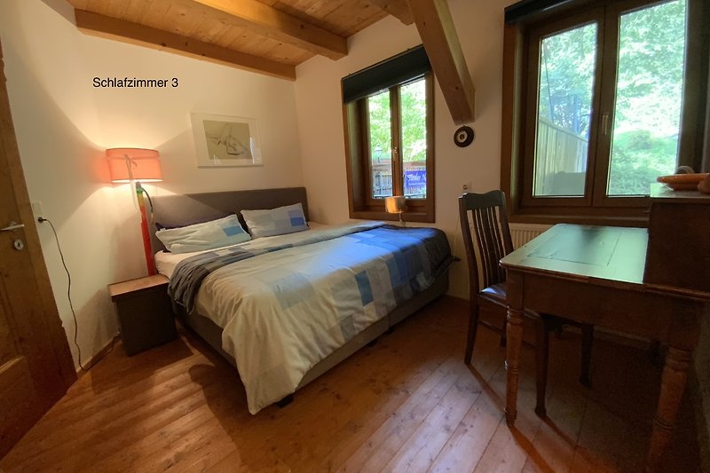 Ein gemütliches Schlafzimmer mit Holzmöbeln und großen Fenstern.