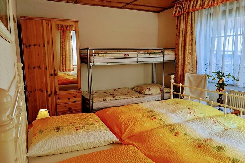 Helles Schlafzimmer I mit Holzmöbeln, Doppelbett und Etagenbett im Erdgeschoss