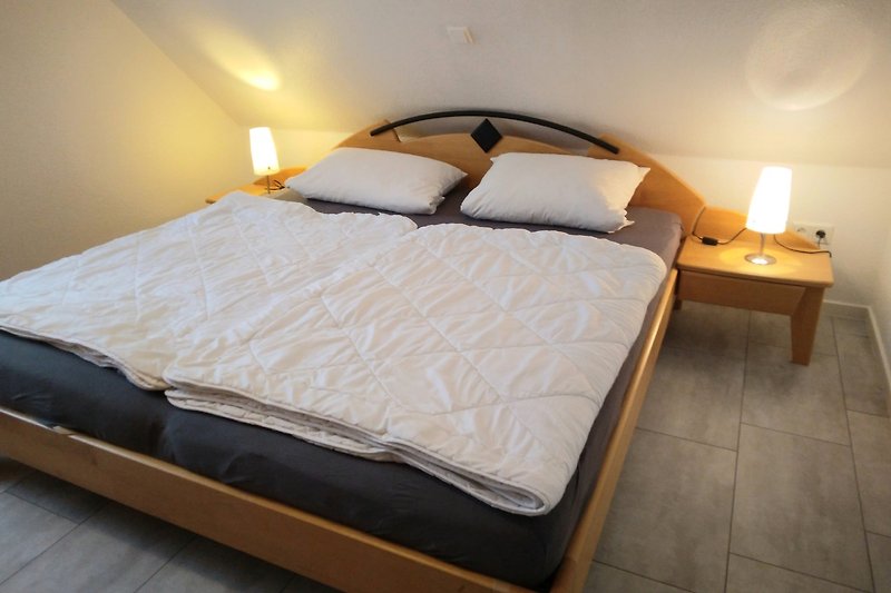 Elegantes Schlafzimmer mit Holzmöbeln, gemütlichem Bett und stilvoller Beleuchtung.