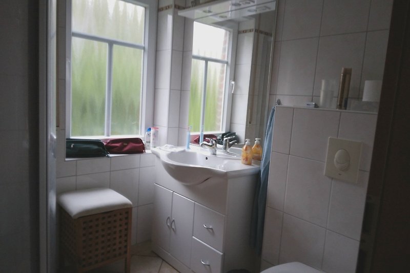 Schönes Badezimmer mit Fliesen, Spiegel, Toilette und Waschbecken.