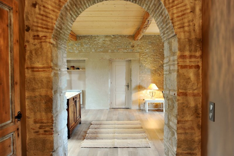 Magnifique intérieur en bois avec des poutres apparentes et une belle porte en briques.