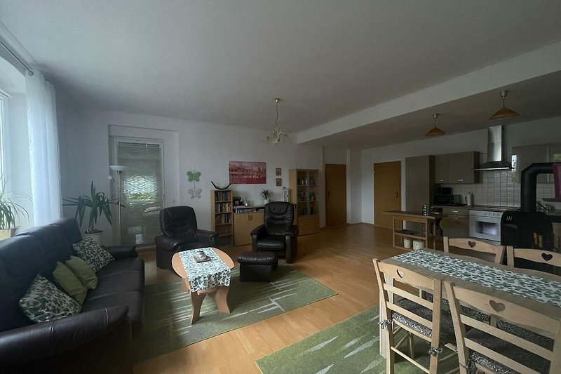 Wohnzimmer mit bequemer Couch, Küchenbereich und Essplatz