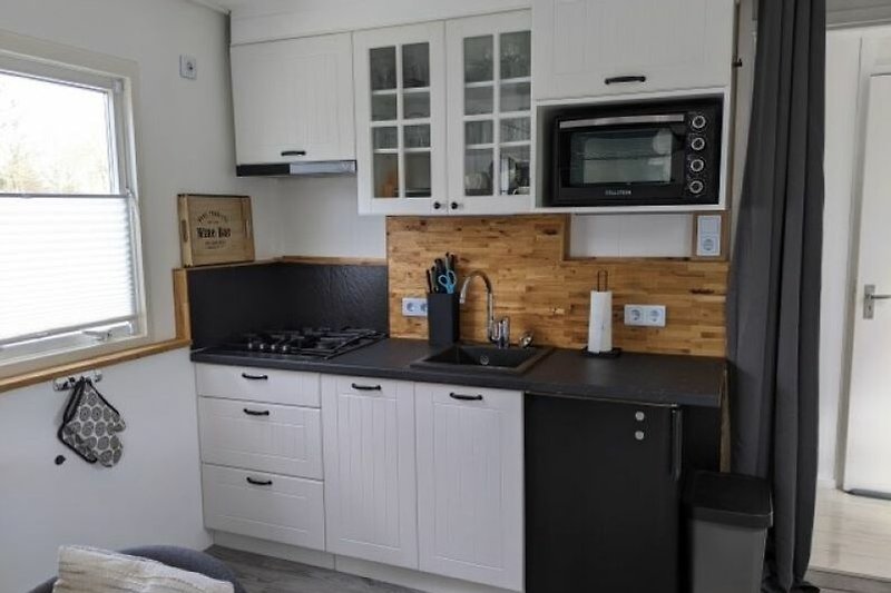 Schöne Küche mit Holzschränken, Fenster und Arbeitsplatte.