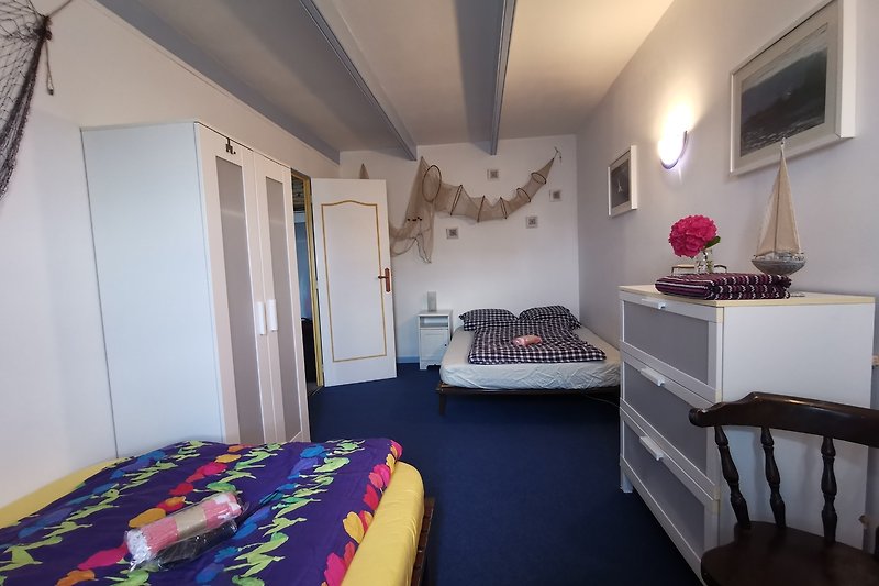 Gemütliches Schlafzimmer im maritimen Stil mit zwei bequemen Betten (jeweils 120 x 190 cm), Kleiderschrank und Kommode.