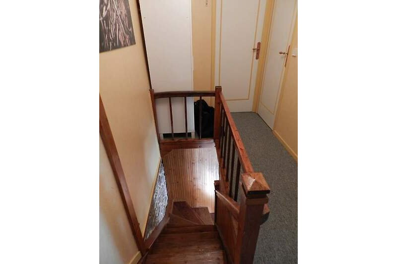 Den Aufgang in die erste Etage bildet diese schöne Holztreppe mit handgefertigtem Geländer .