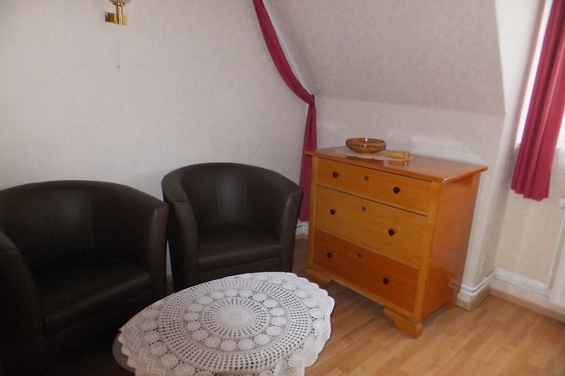 Schlafzimmer mit Sessel, Tisch und Kommode