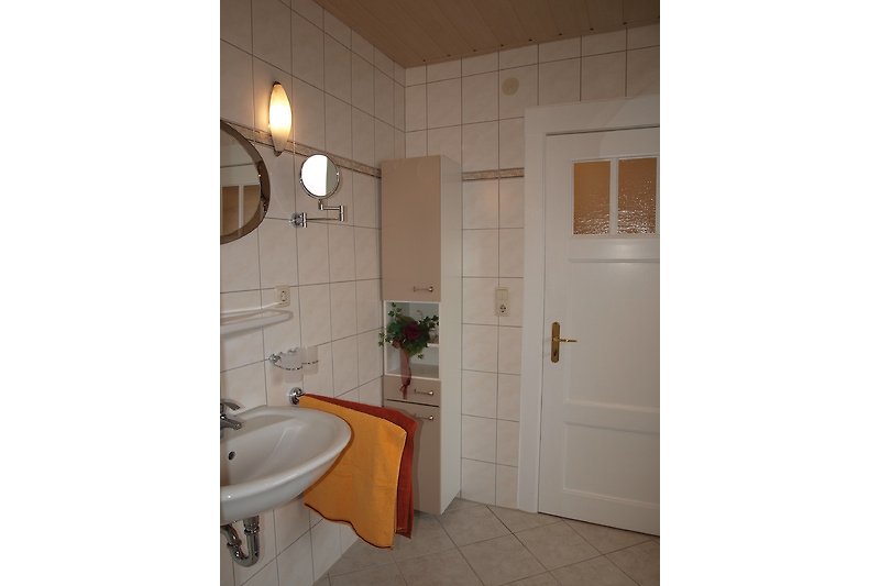 Badezimmer mit Spiegel, Waschbecken und stilvoller Beleuchtung.