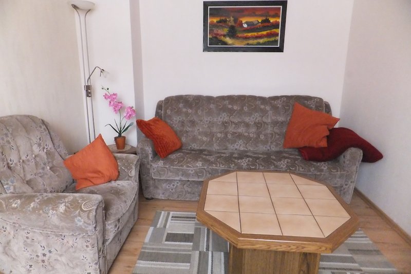 Gemütliches Wohnzimmer mit bequemer Couch und stilvollem Holzmöbel.