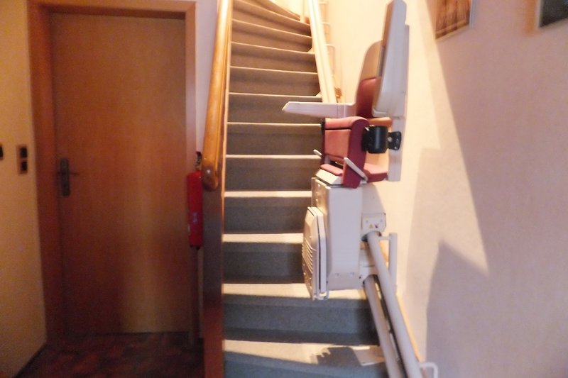 Schöne Holztreppe mit handgefertigtem Geländer und stilvollem Holzboden. Treppenlift