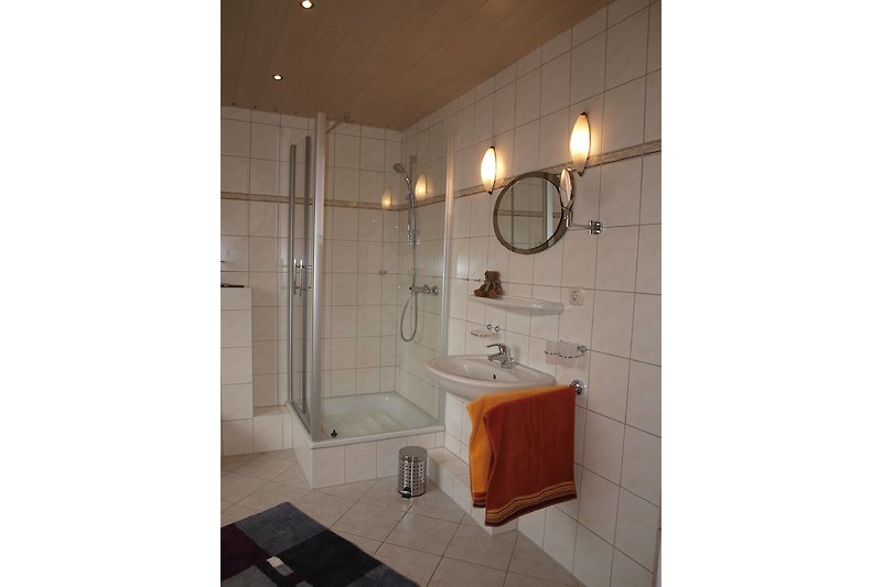 Badezimmer mit stilvoller Beleuchtung, Spiegel, Waschbecken und Dusche