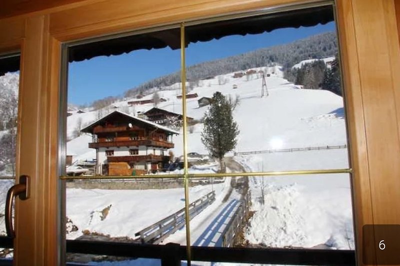 Blick aus der Küche auf verschneite Berge  und winterliche Landschaft.