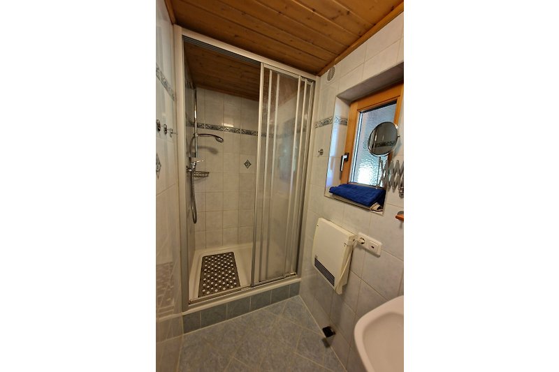 Badezimmer mit Waschbecken, Spiegel, Fenster und Fliesenboden.