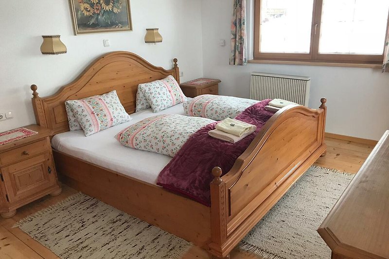 Gemütliches Schlafzimmer mit Holzmöbeln und gemütlichem 2m x 2m Bett.